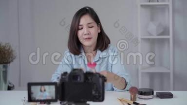 快乐微笑的亚洲女人或美女博主用画笔和<strong>相机录制</strong>视频，并在家挥手。